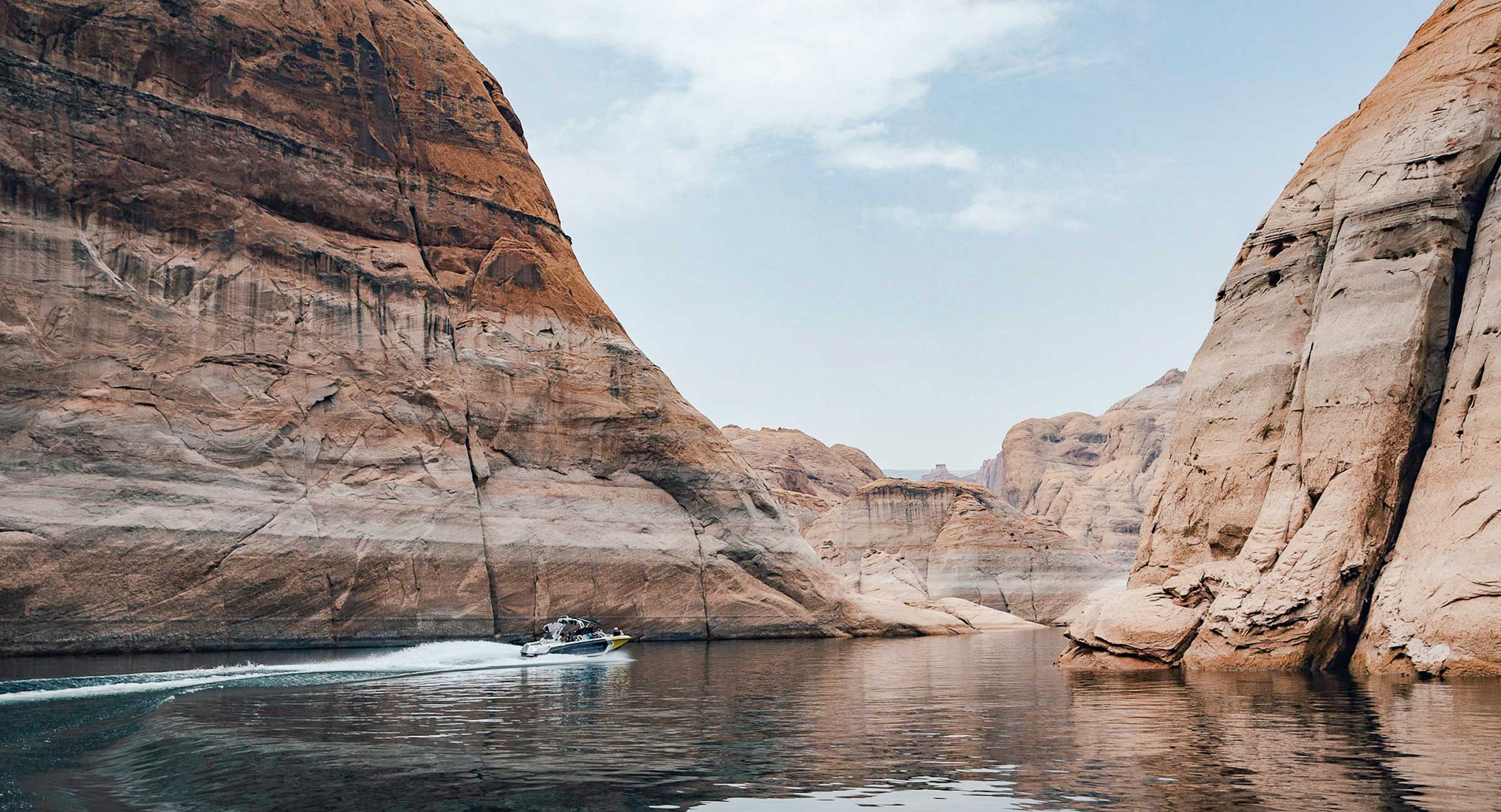 A small boat winds through back canyons on Lake Powell.