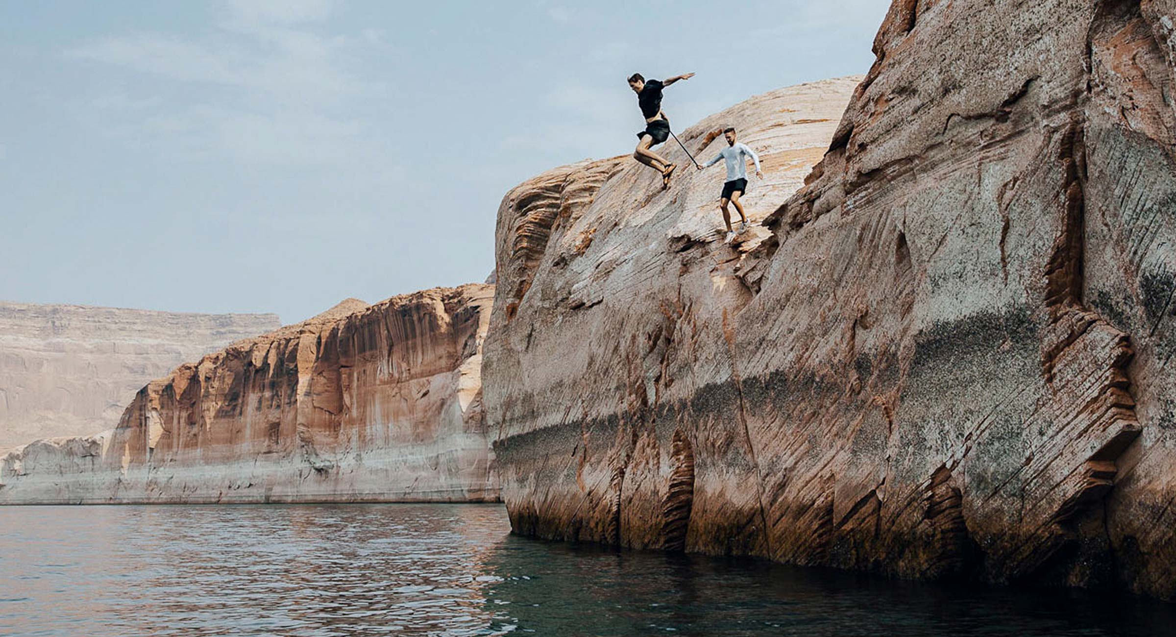 A person jumps off a cliff into Lake Powell.