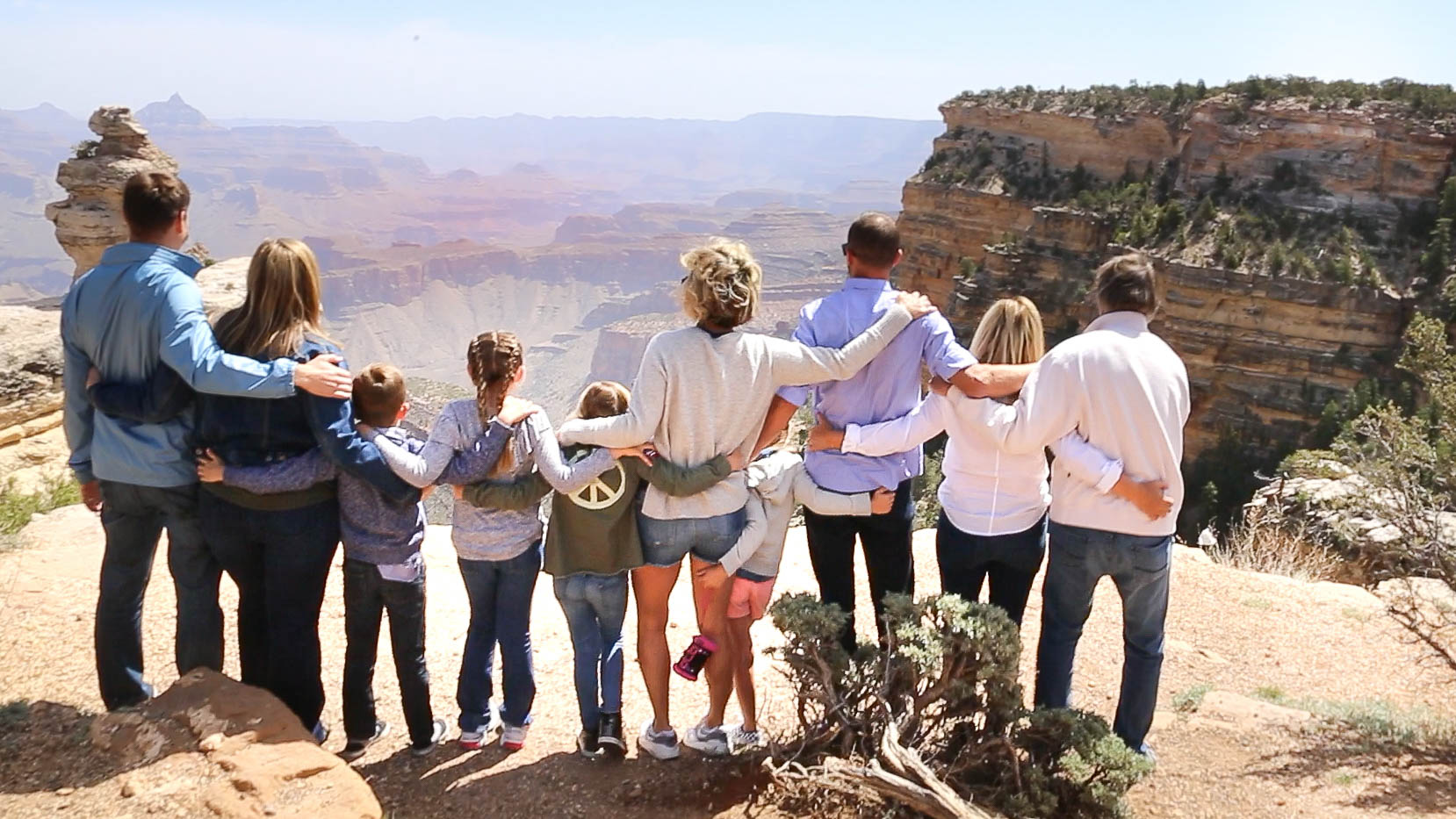 A family stands together looking out over the Grand Canyon.