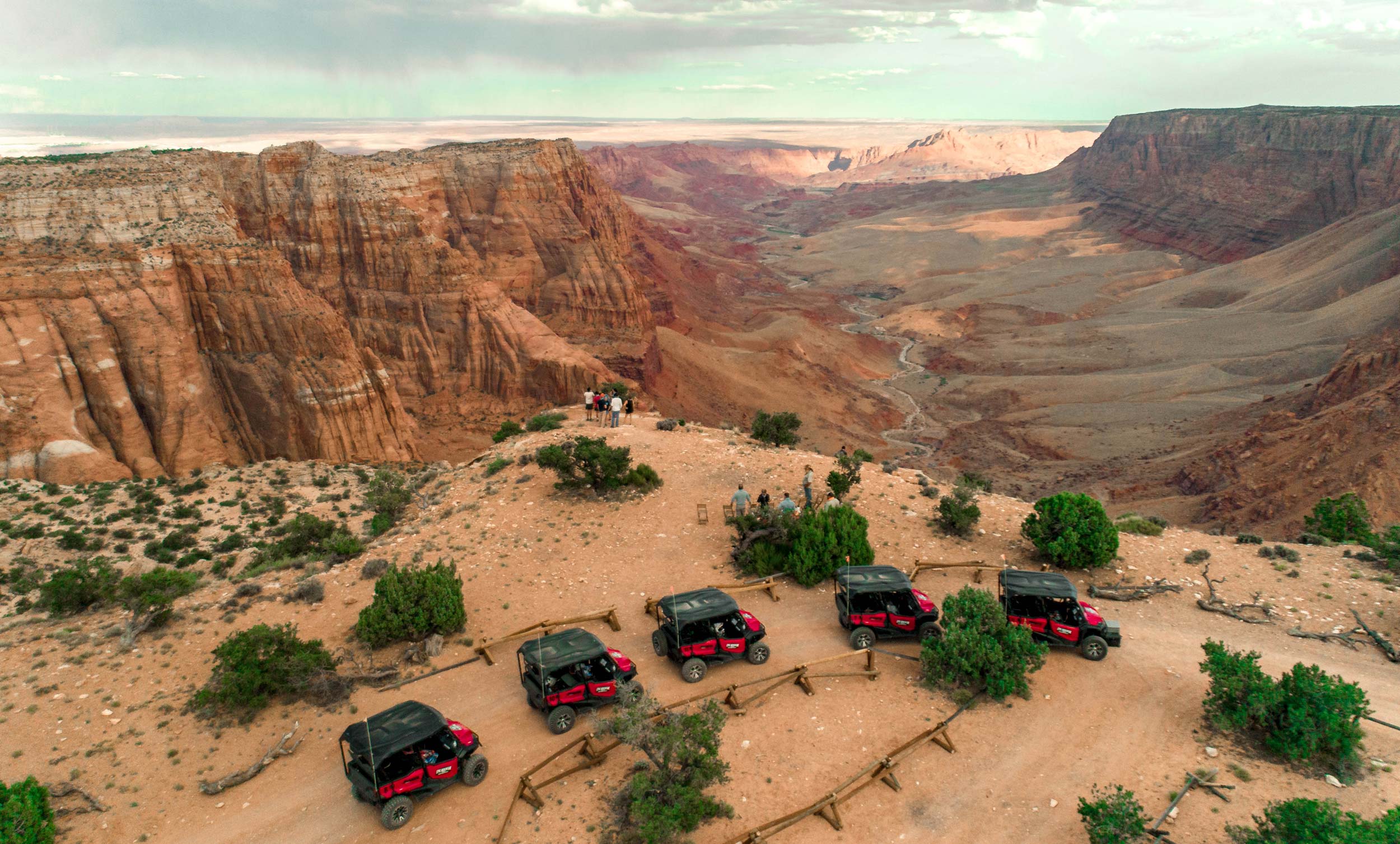 A group stands over a cliff looking at Vermillion Cliffs during their UTV tour.
