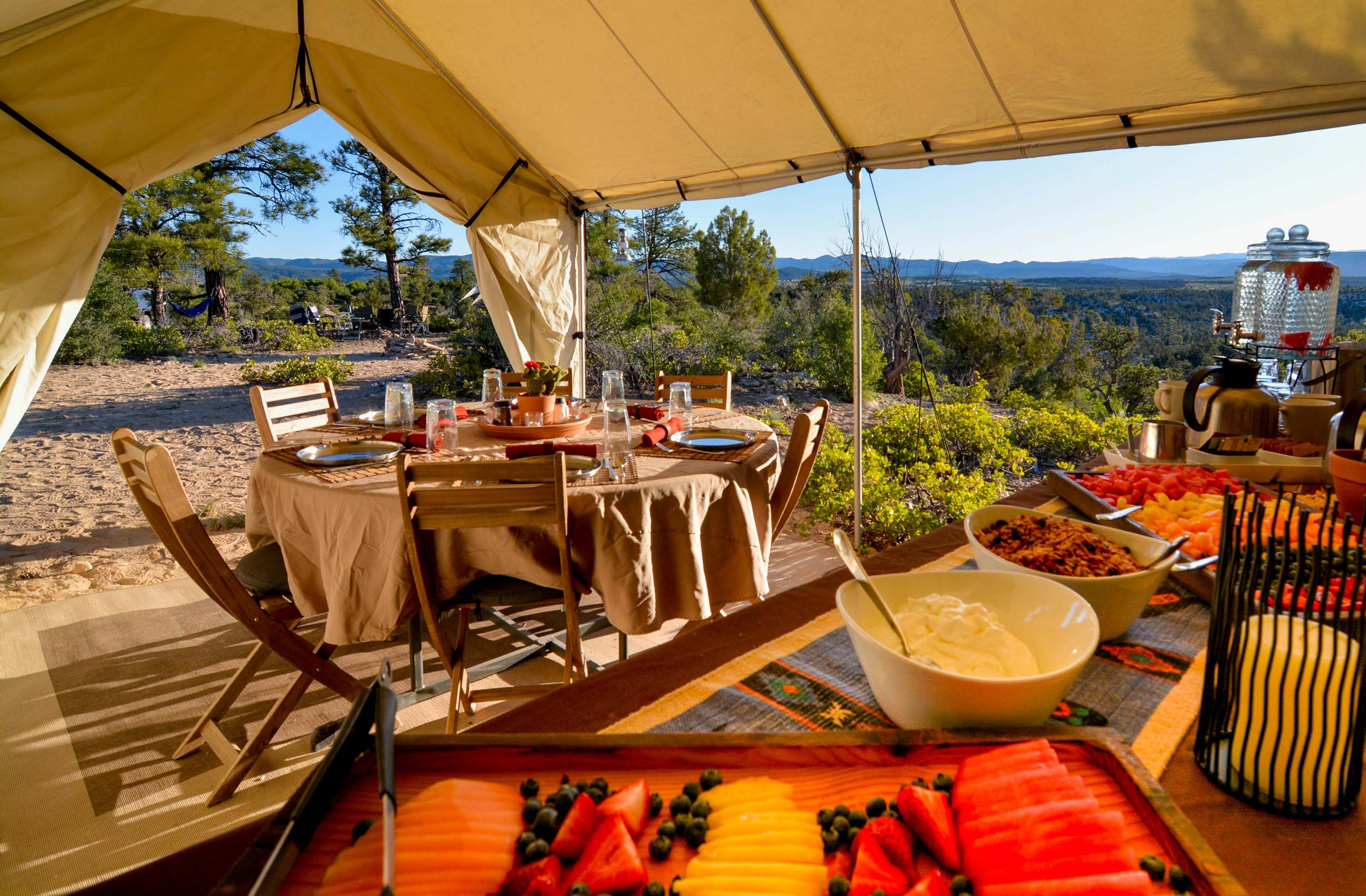 A gourmet brunch spread inside of a luxury camp tent with mountains in the distance.