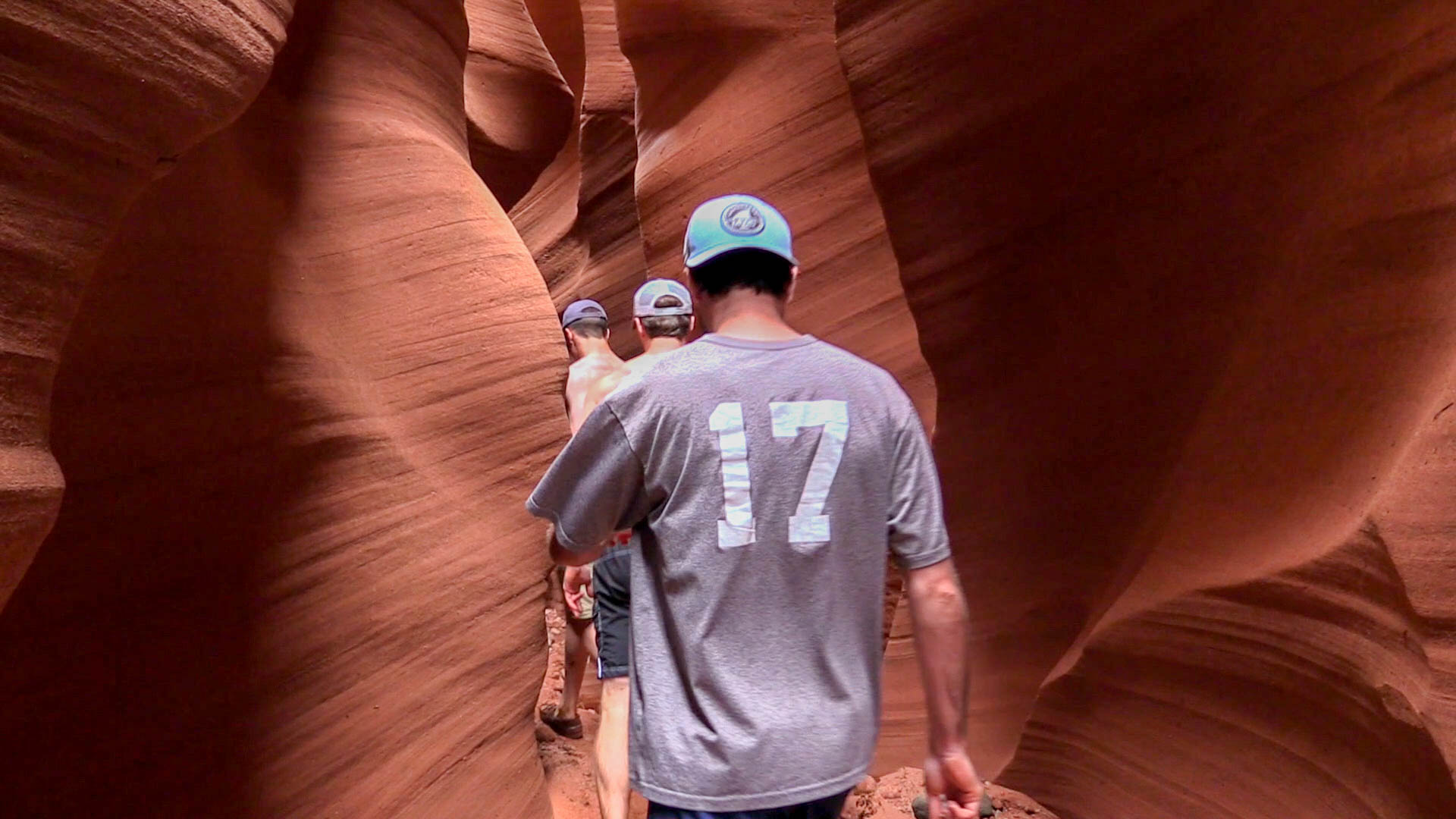 A group of men wander through a slot canyon.