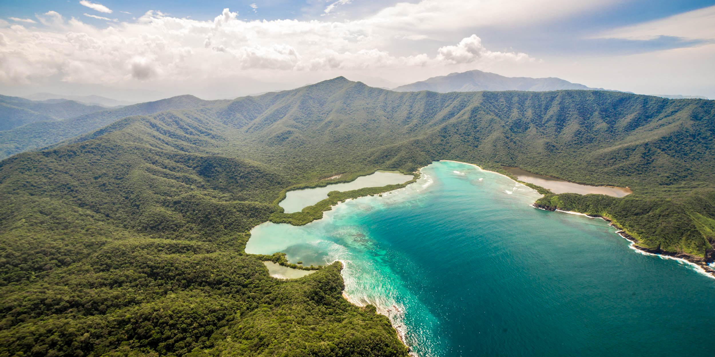 Aerial view of the lush, green mountains and turquoise coastal waters of the Sierra Nevada de Santa Marta.