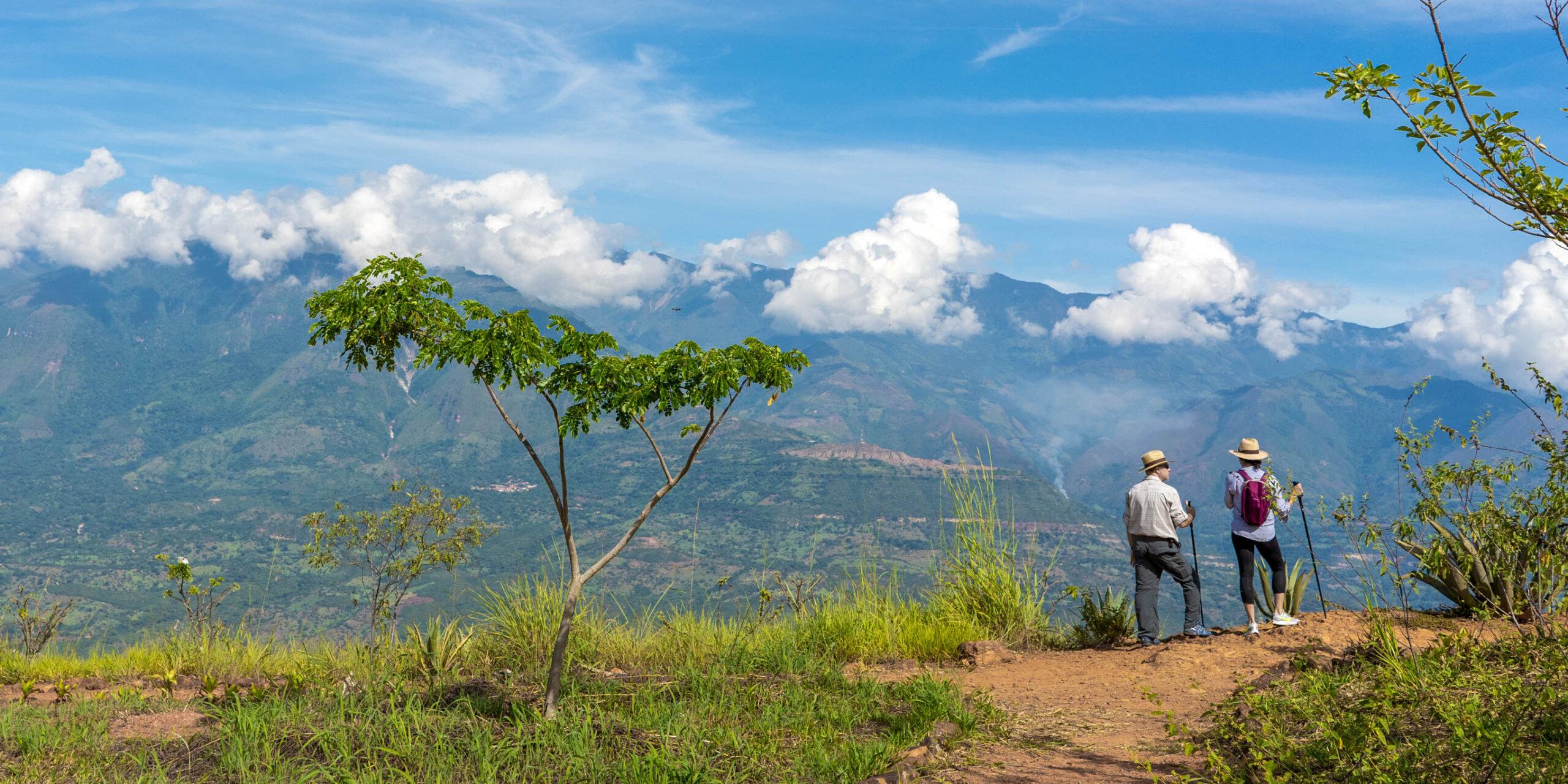 yariguies.JPG Two hikers in straw hats on a ridge overlooking rolling green mountains under a bright blue, cloudy sky.