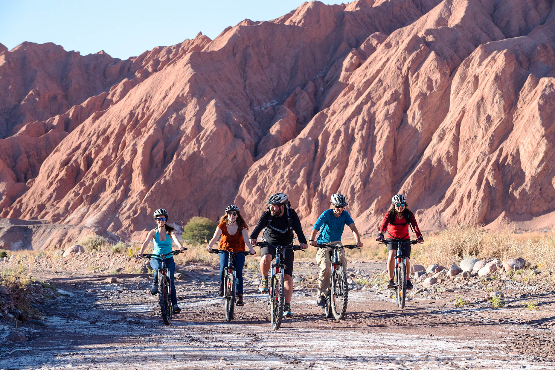 A group of people bike through a canyon to a ghost town in the Southwest.