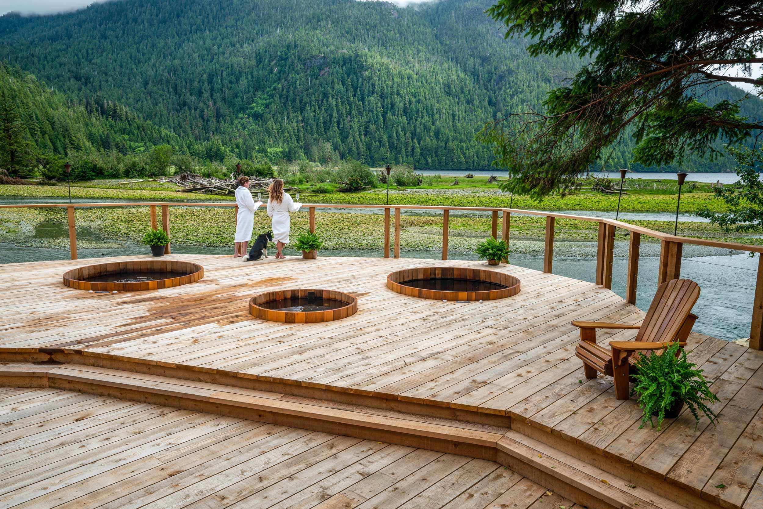 Women stand on a spa deck looking at Canada's wilderness.