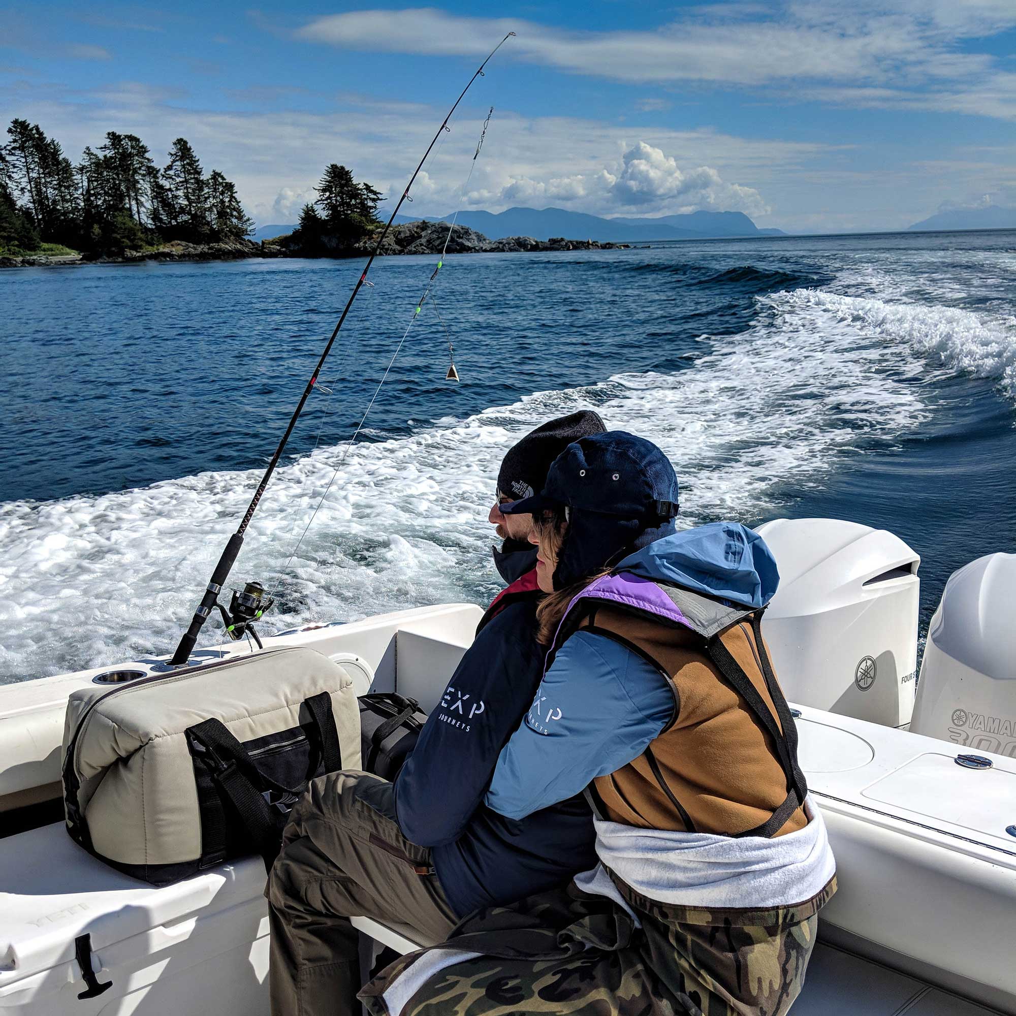 A couple hugs each other on a boat while fishing.