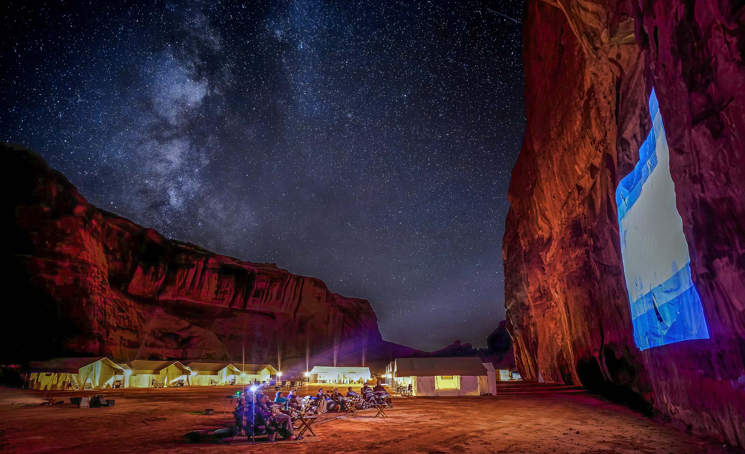 People gather in Monument Valley at night to watch a movie projected onto the rocks.