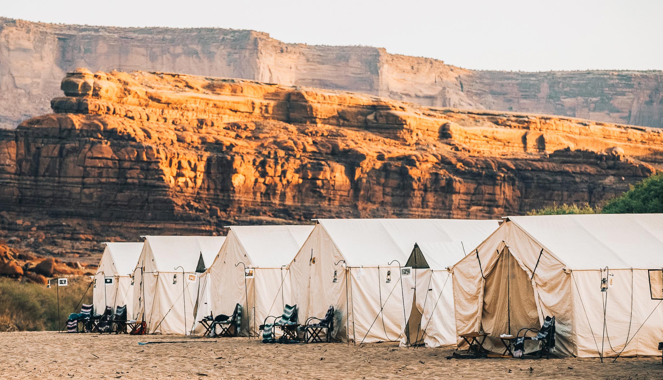 Luxury camping tents at sunrise with the towering mountains in the distance.