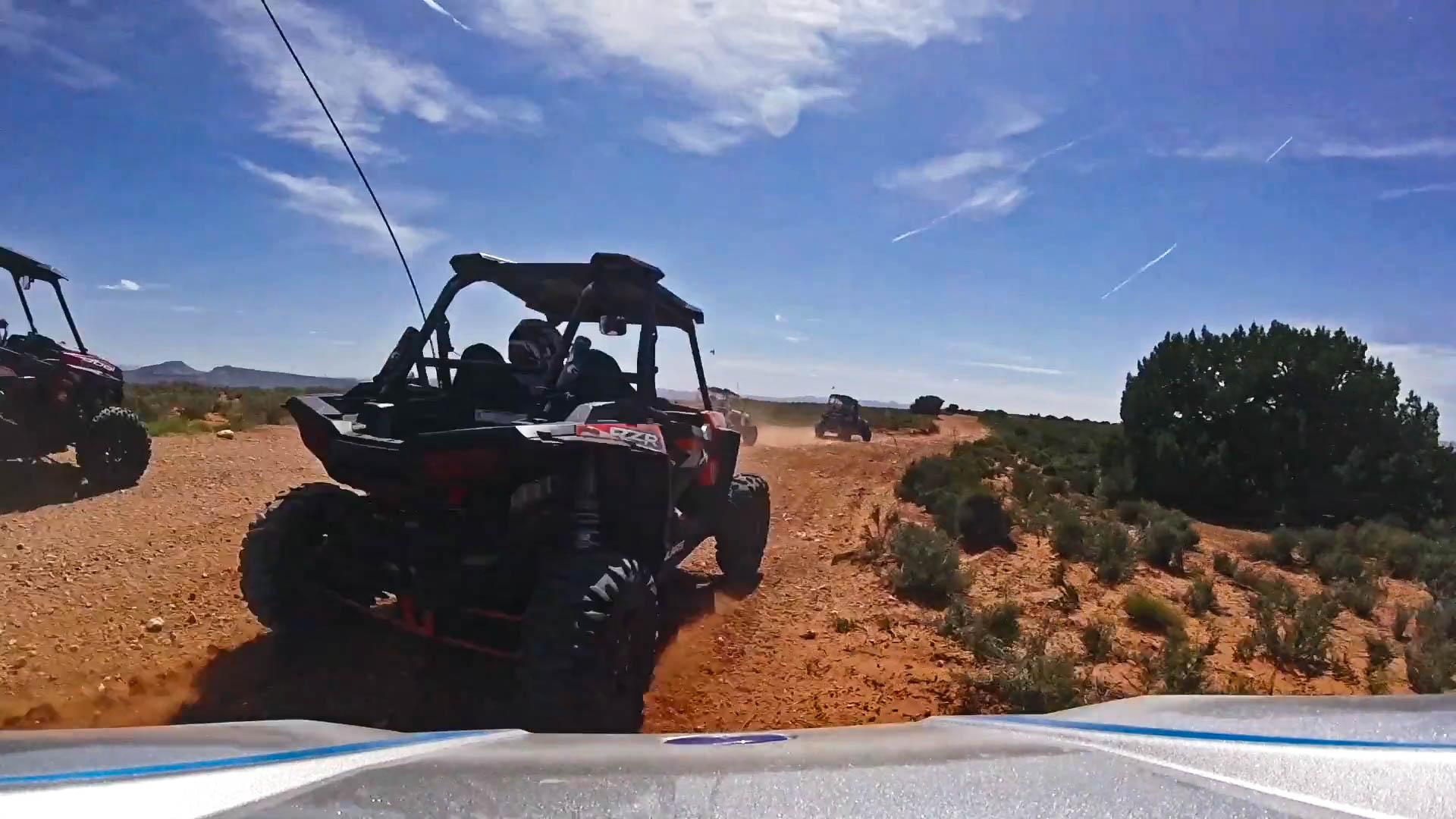 Friends race through the desert in UTVs.