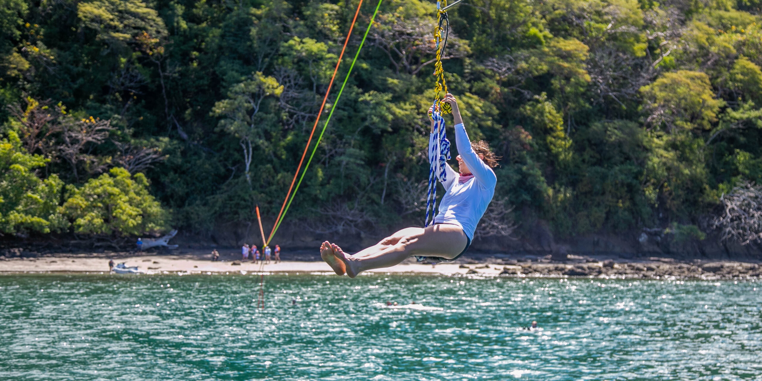 A woman zip lines from a private boat across the water in Costa Rica.