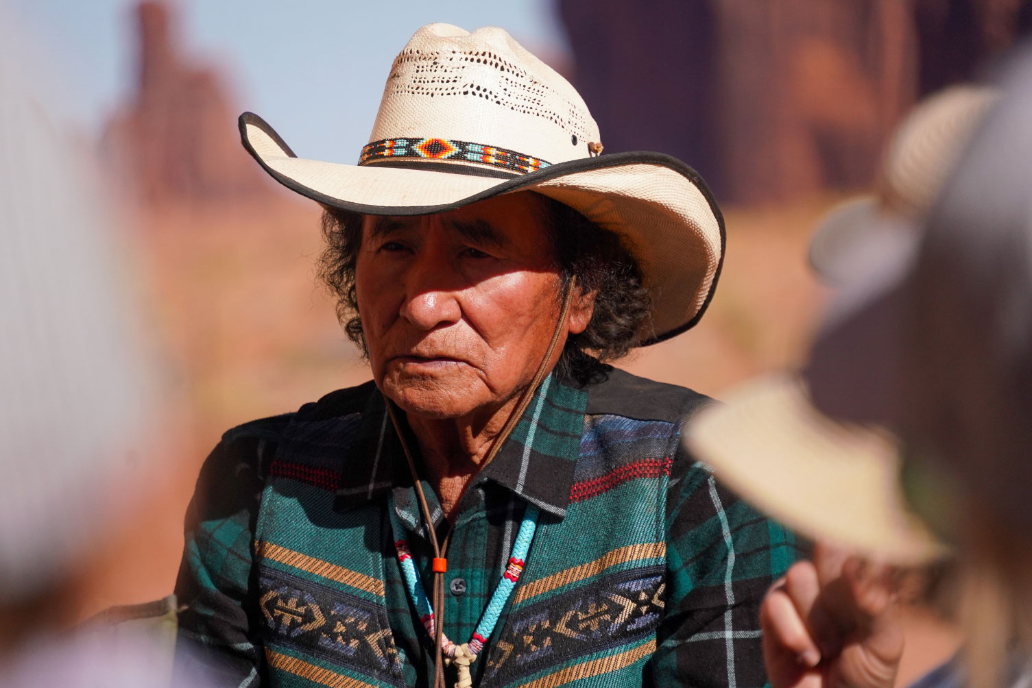 storytelling-yee-haolnii-doo A Native American guide wearing a cowboy hat, plaid shirt, and turquoise necklace tells stories with a desert background.