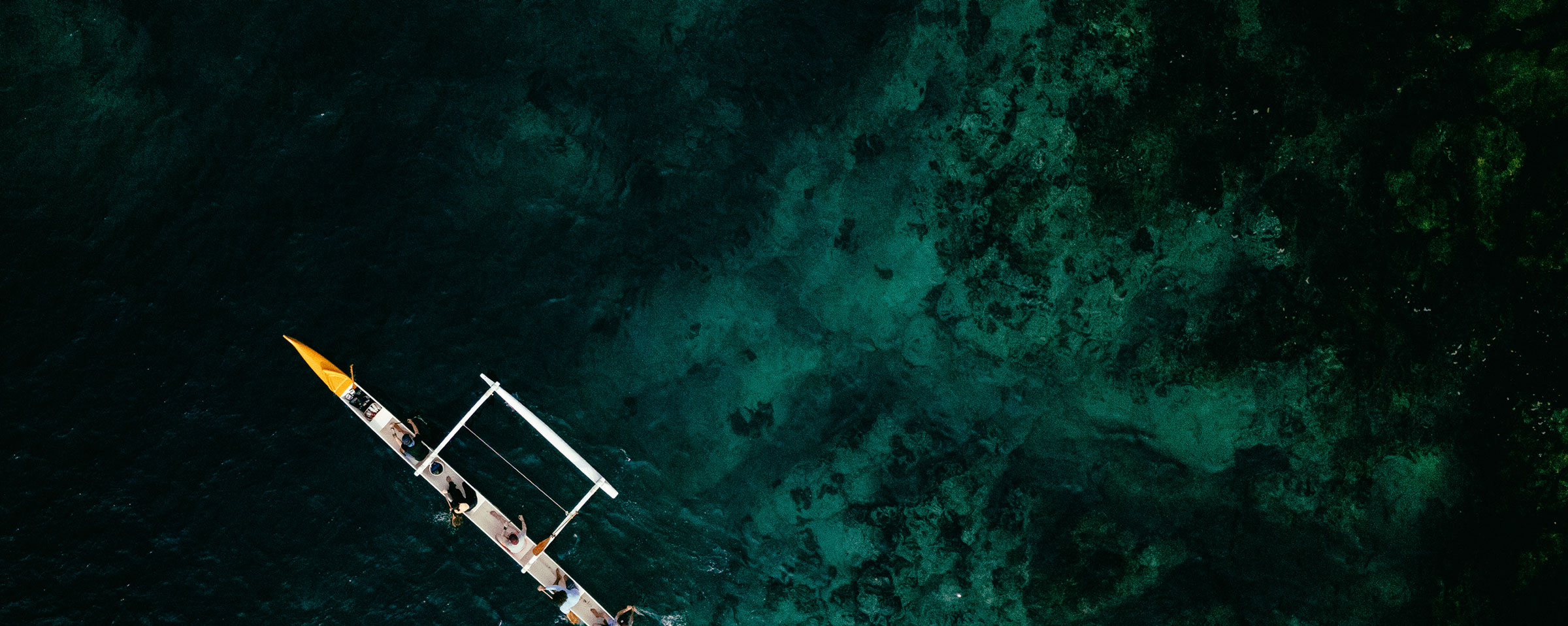 Costa-Rica-Header - EXP Journeys Top-down view of an outrigger boat gliding over a vibrant reef in Costa Rica.