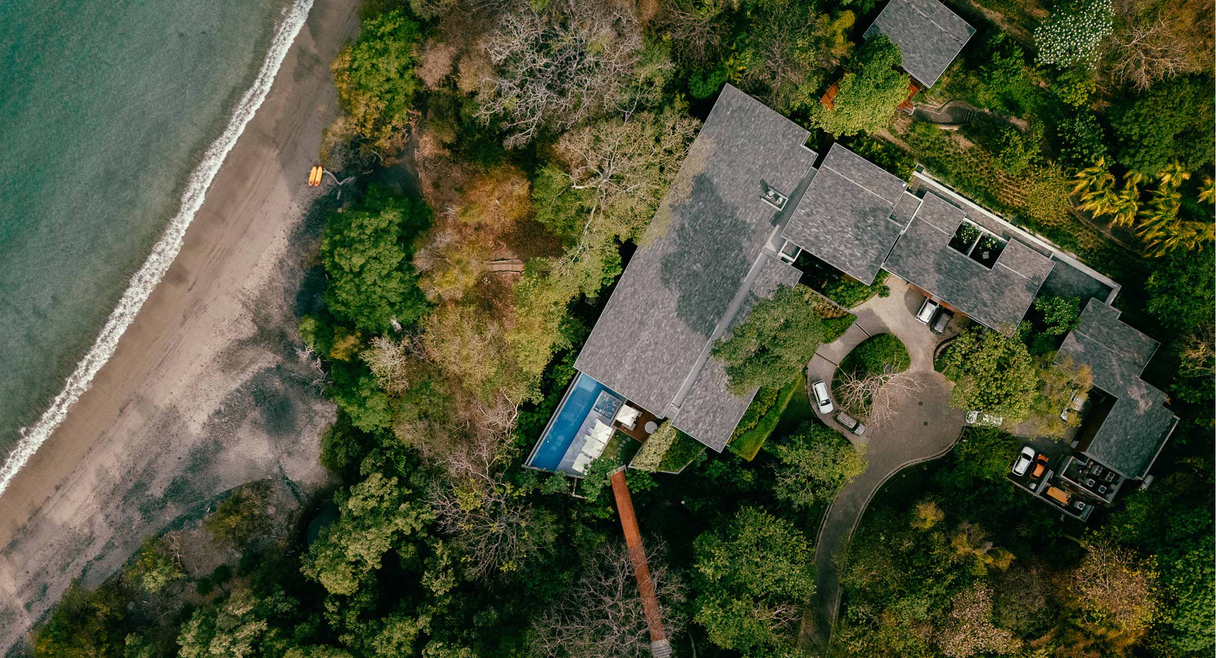 costa-rica-accommodation Aerial view of a luxury travel villa in Costa Rica, featuring a private lap pool nestled between a lush tropical jungle and a secluded beach.