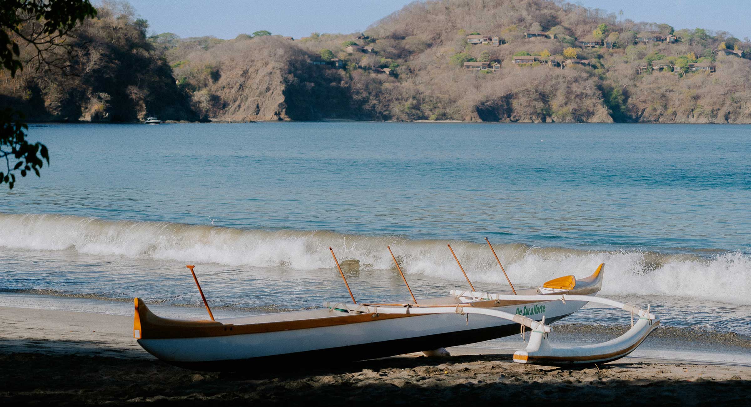 costa-rica-fishing A traditional outrigger canoe on a serene beach in Costa Rica.