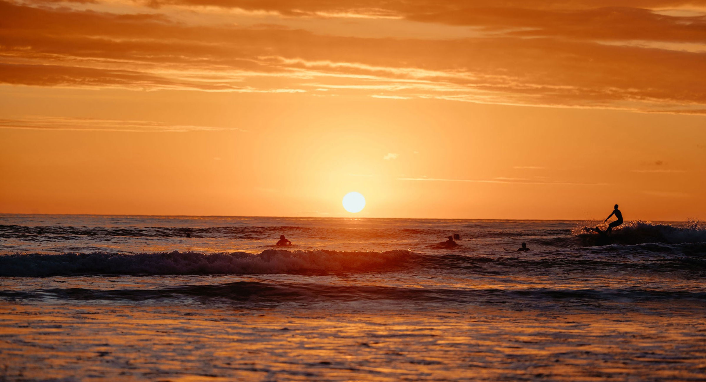 costa-rica-sunset A breathtaking sunset over the Pacific, with surfers catching the last waves of the day.
