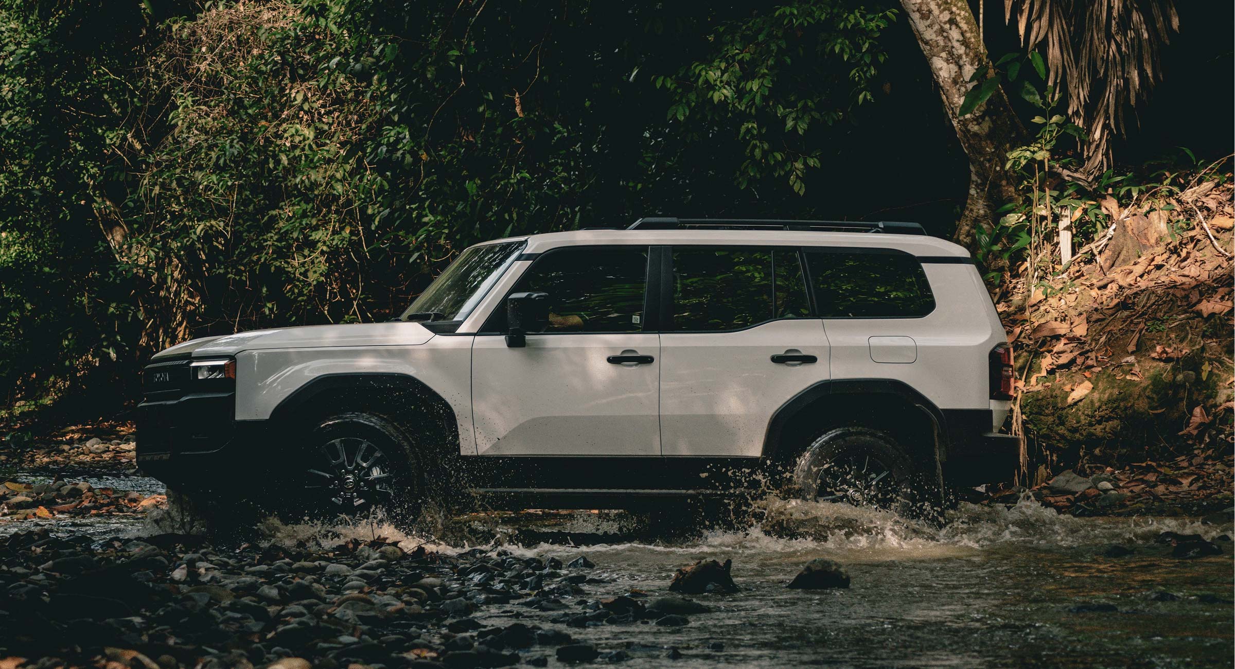 costa-rica-trekking A modern white 4x4 vehicle splashing through a shallow jungle river, highlighting the rugged yet comfortable transport on a Costa Rica expedition.