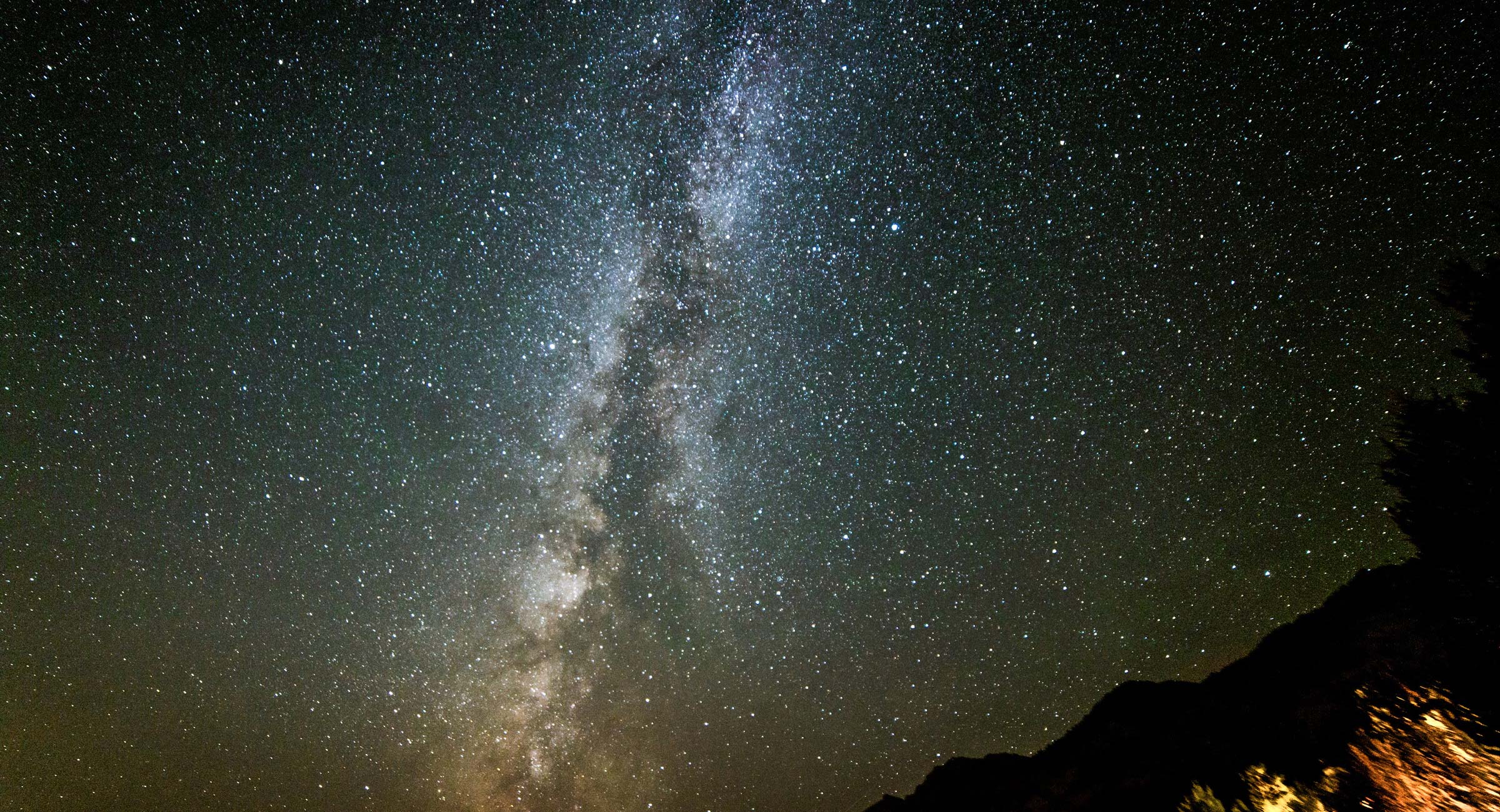 montana-stargazing - EXP Journeys - EXP Journeys Milky Way band across a star-filled night sky with rocky silhouettes along the bottom edge.